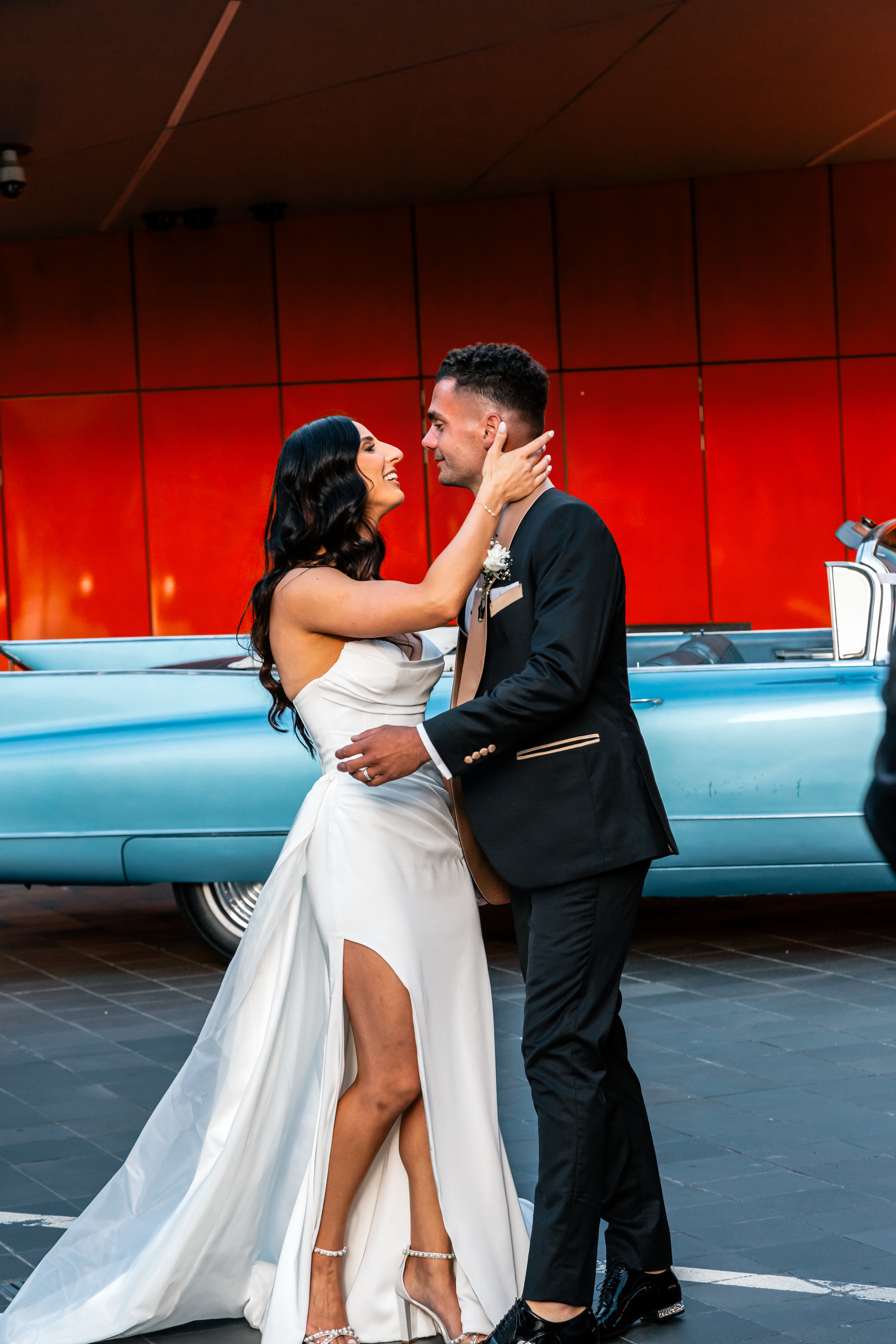 Stylish bridal couple laughing and walking together beside a classic car, natural light candid wedding photography Melbourne VIC, fun and relaxed wedding vibes Yarra Valley and Mornington Peninsula
